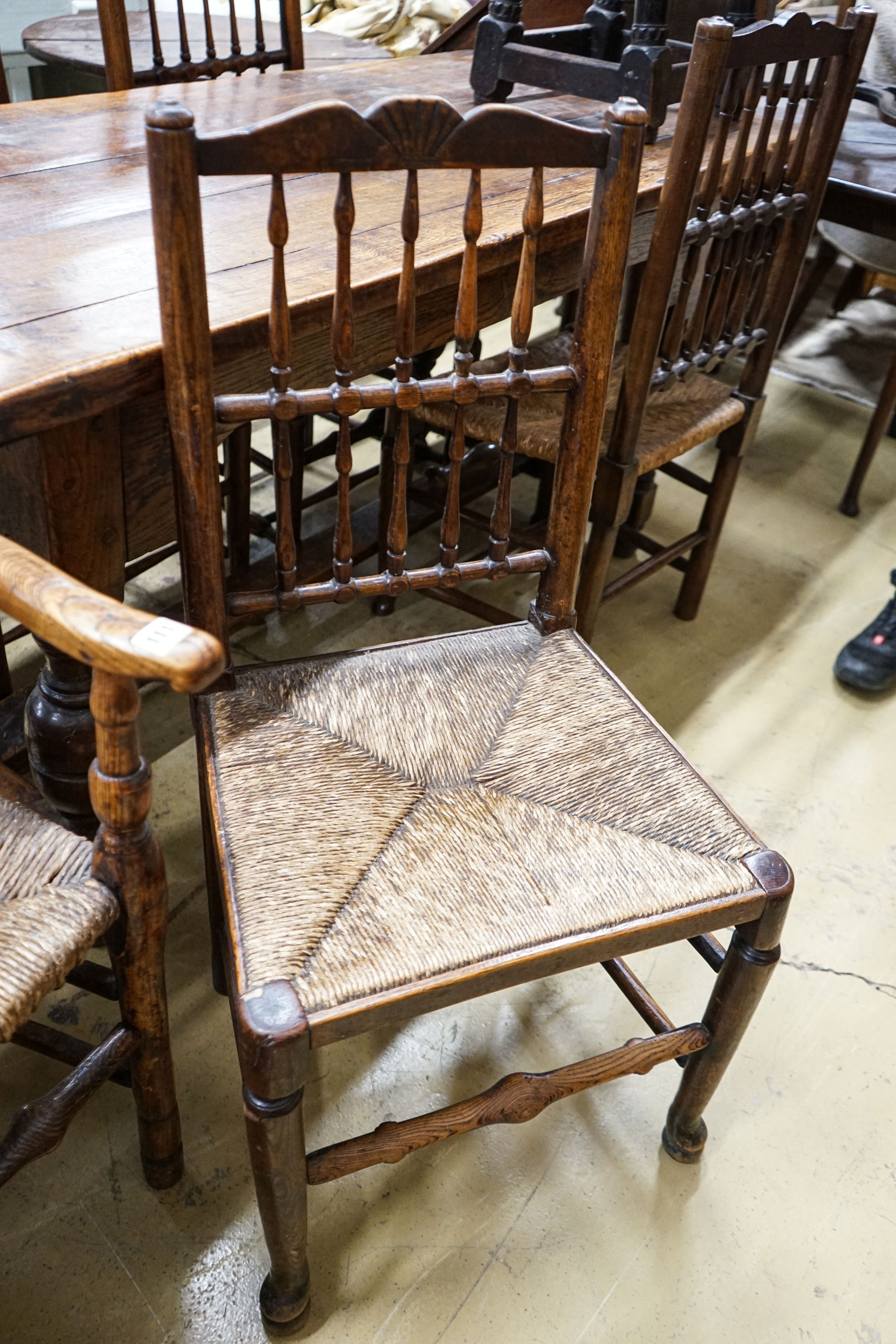 A harlequin set of five oak, elm and beech spindle back chairs, with rush seats and a similar ladderback carver